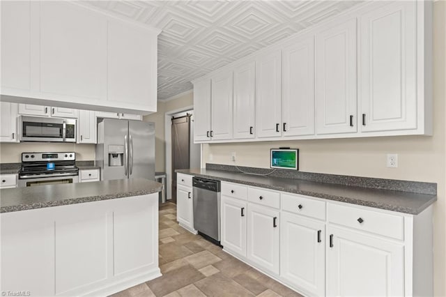 kitchen with white cabinets, a barn door, and appliances with stainless steel finishes