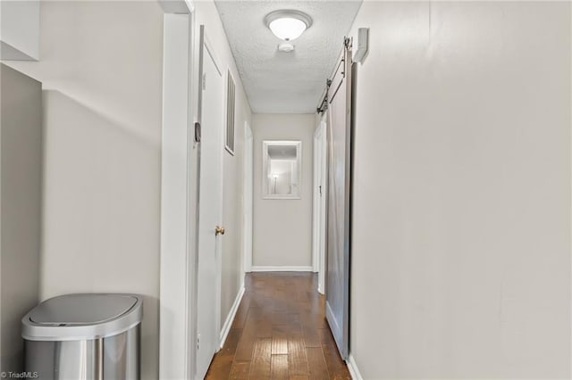 corridor featuring a textured ceiling, dark hardwood / wood-style floors, and a barn door