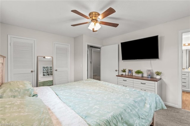 carpeted bedroom featuring connected bathroom, two closets, and ceiling fan