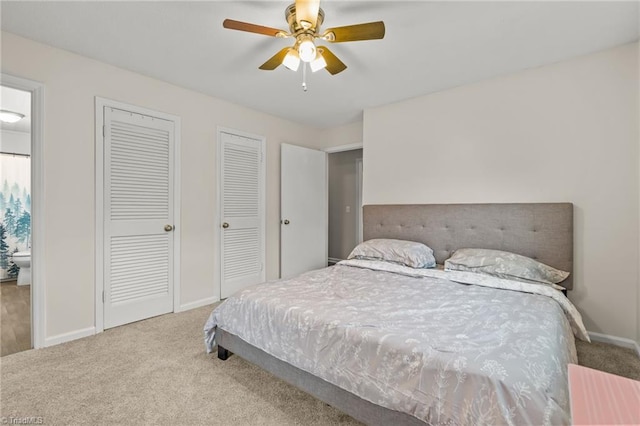 carpeted bedroom with ceiling fan and two closets