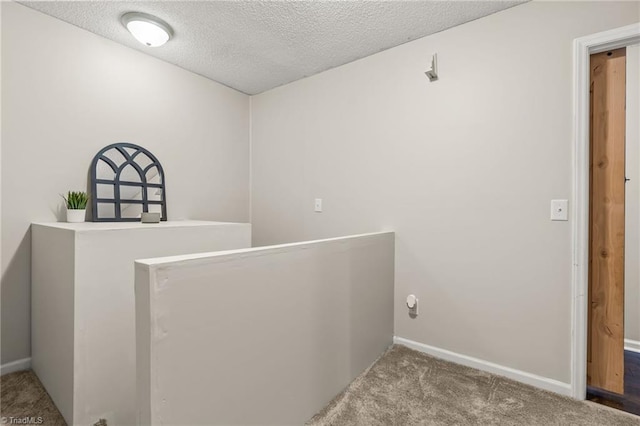 hallway with light colored carpet and a textured ceiling