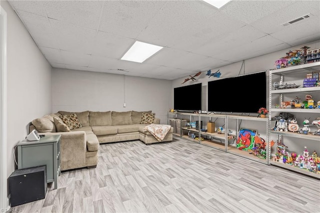 living room featuring light wood-type flooring and a drop ceiling