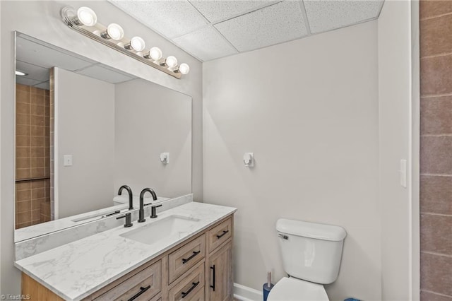 bathroom featuring a drop ceiling, toilet, and vanity