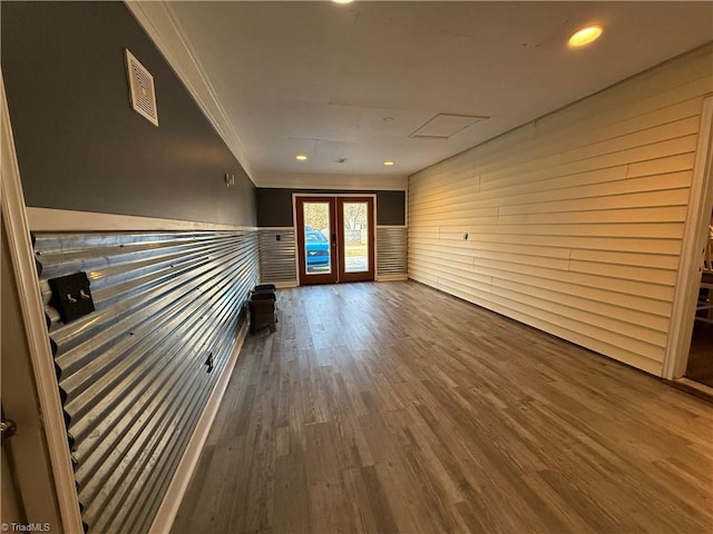 unfurnished living room with crown molding, dark wood-type flooring, and french doors