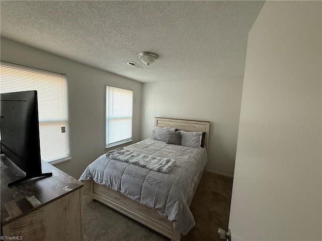 bedroom featuring dark carpet and a textured ceiling