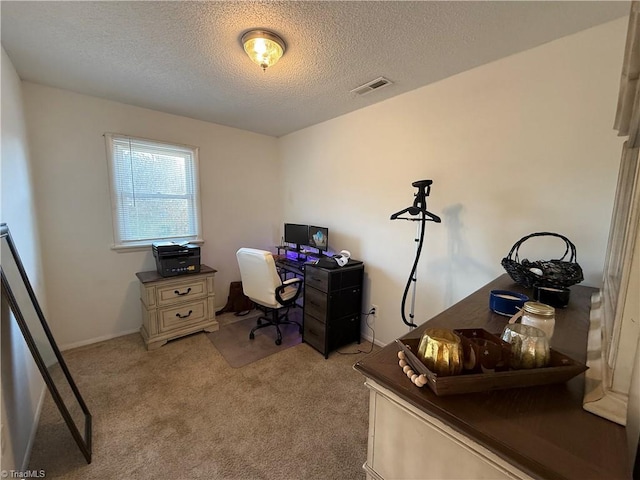 carpeted home office featuring a textured ceiling