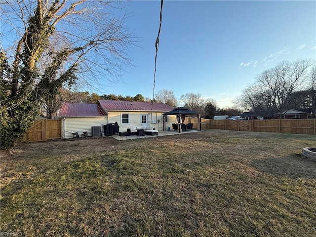 rear view of house with a gazebo, central AC, and a lawn