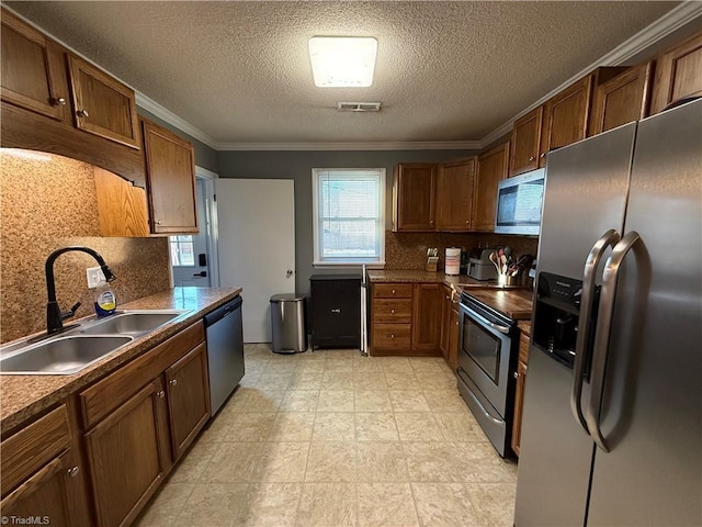 kitchen featuring stainless steel appliances, ornamental molding, sink, and tasteful backsplash