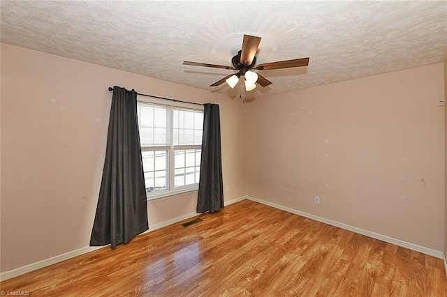 spare room featuring visible vents, light wood-style flooring, a textured ceiling, and baseboards