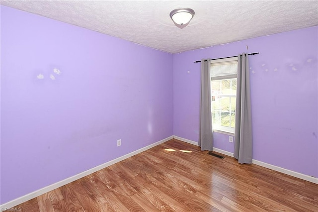 unfurnished room with light wood-style floors, visible vents, and baseboards