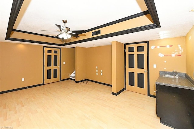 spare room featuring a sink, a tray ceiling, visible vents, and light wood finished floors