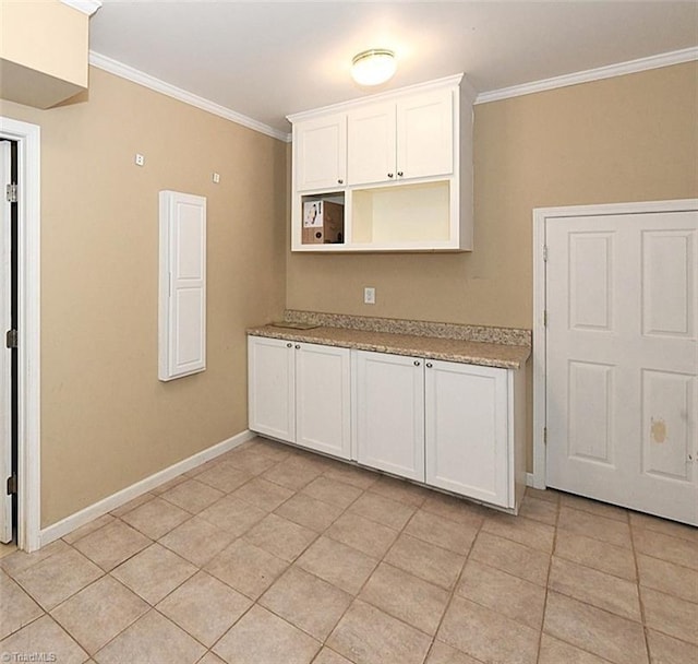 kitchen with white cabinets, light countertops, baseboards, and ornamental molding