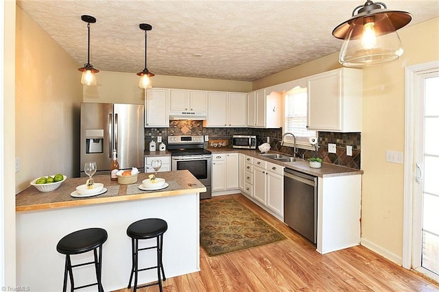 kitchen with white cabinetry, light wood-style flooring, appliances with stainless steel finishes, and a sink