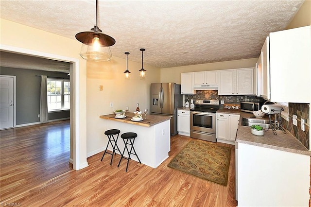 kitchen with decorative backsplash, light wood-style flooring, white cabinets, and stainless steel appliances