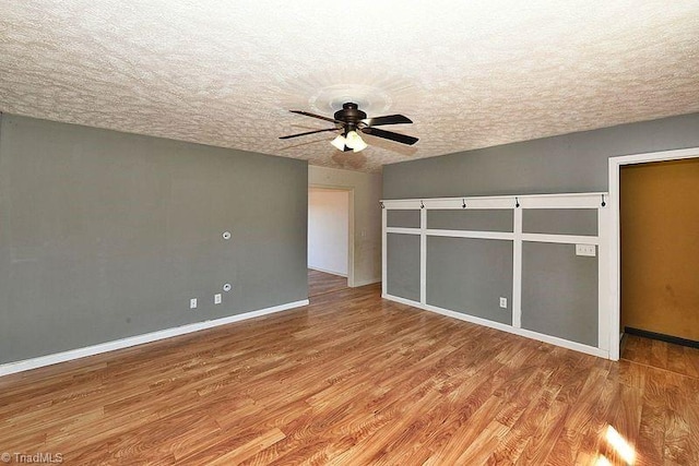 unfurnished bedroom featuring baseboards, a textured ceiling, wood finished floors, and a ceiling fan