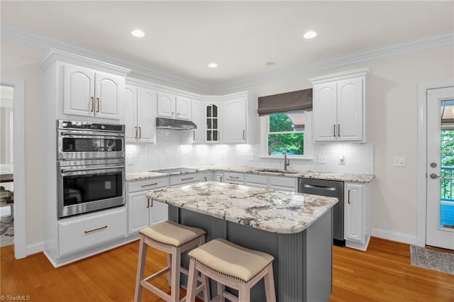 6707 Fegan Rd, Summerfield, NC 27358 - kitchen with stainless steel appliances, under cabinet range hood, a breakfast bar area, plenty of natural light, and crown molding