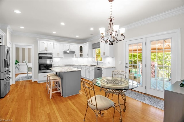 6707 Fegan Rd, Summerfield, NC 27358 - kitchen featuring stainless steel appliances, a kitchen island, under cabinet range hood, white cabinetry, and crown molding