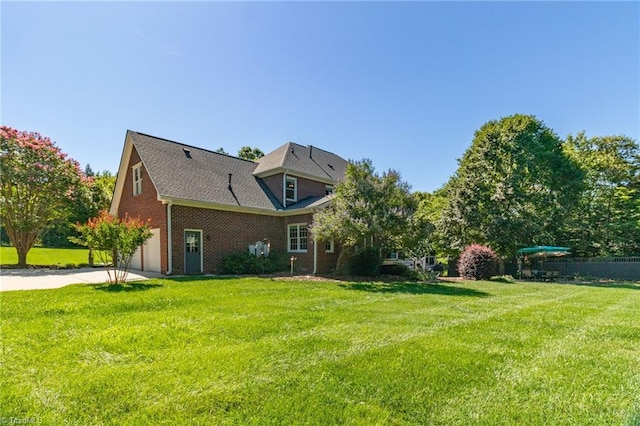 6707 Fegan Rd, Summerfield, NC 27358 - rear view of house featuring a yard, driveway, brick siding, and an attached garage