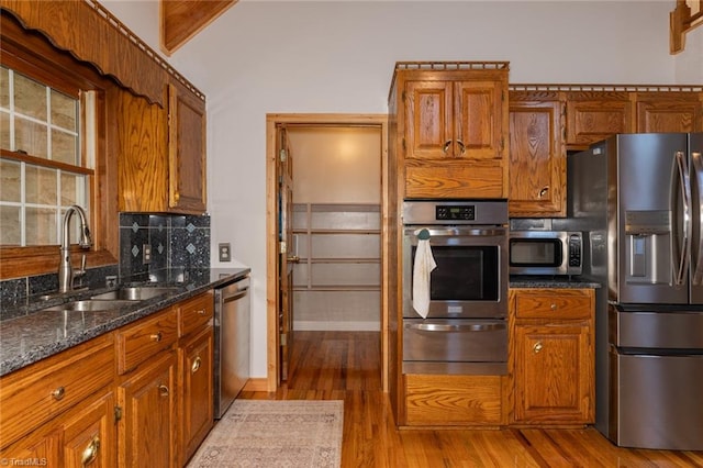 kitchen featuring dark stone counters, stainless steel appliances, backsplash, and hardwood / wood-style floors