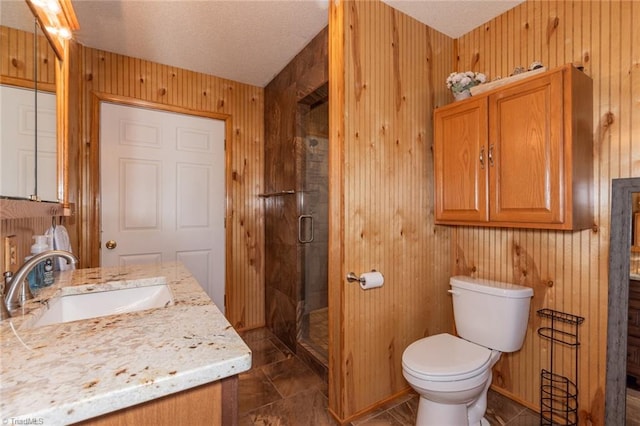 bathroom featuring wood walls, toilet, vanity, and an enclosed shower