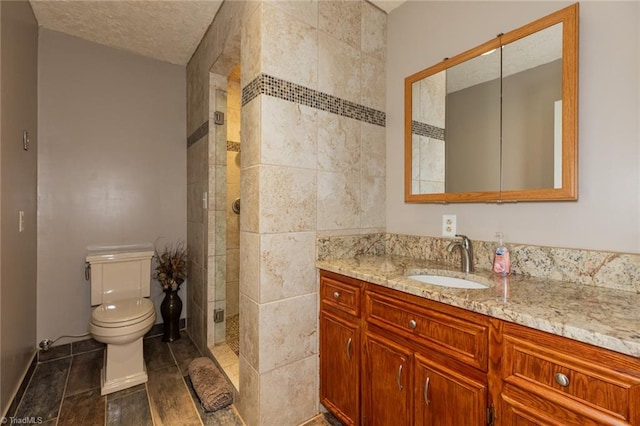 bathroom with vanity, toilet, a tile shower, and tile patterned flooring