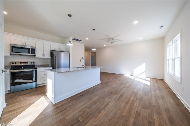 kitchen featuring ceiling fan, white cabinetry, hanging light fixtures, an island with sink, and appliances with stainless steel finishes