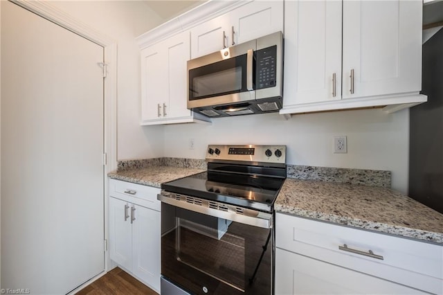 kitchen featuring white cabinets, dark hardwood / wood-style flooring, light stone countertops, and appliances with stainless steel finishes