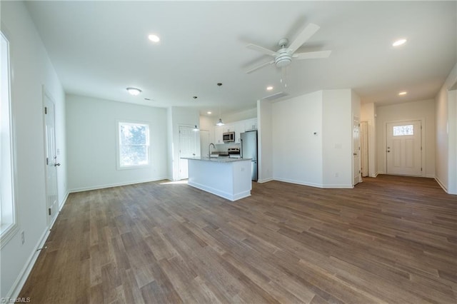 unfurnished living room featuring ceiling fan, sink, and dark hardwood / wood-style floors