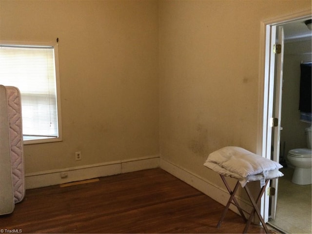 unfurnished room with baseboards and dark wood-style flooring