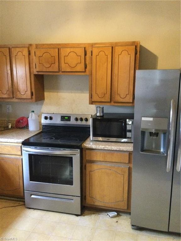 kitchen featuring brown cabinetry, appliances with stainless steel finishes, and light countertops