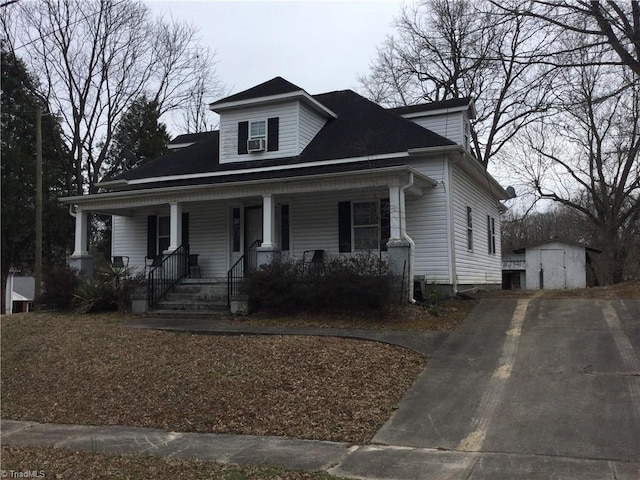 bungalow-style home with an outdoor structure, a storage unit, and covered porch