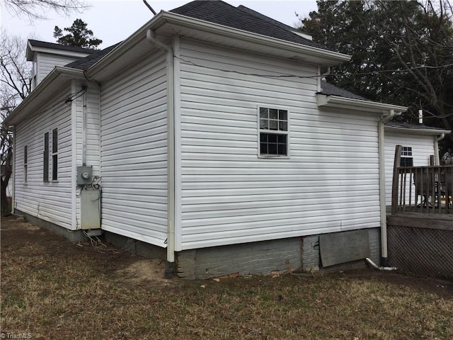 view of side of home featuring roof with shingles and a wooden deck