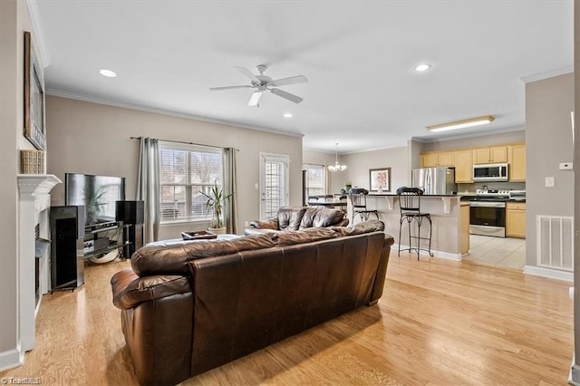 living room featuring ceiling fan with notable chandelier, light hardwood / wood-style floors, and crown molding