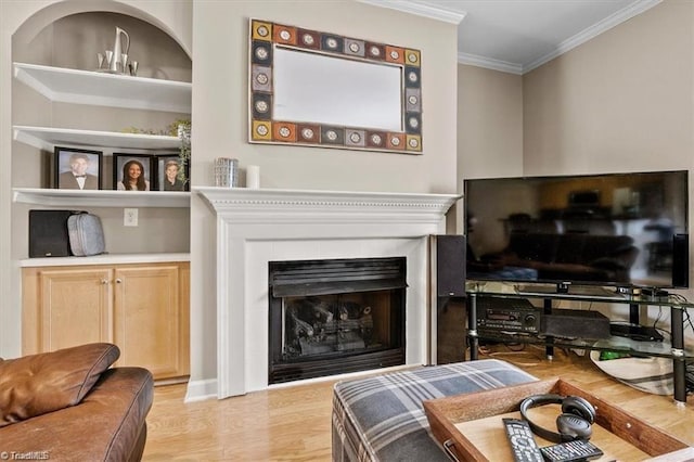 living room with light hardwood / wood-style floors, built in shelves, and crown molding