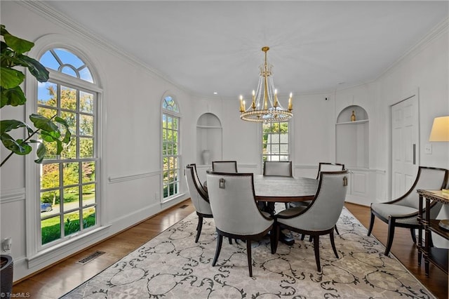 dining space with visible vents, ornamental molding, an inviting chandelier, and plenty of natural light