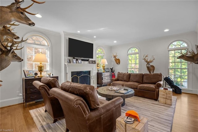 living room featuring light wood finished floors, recessed lighting, a fireplace, crown molding, and baseboards