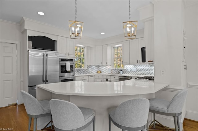 kitchen with decorative backsplash, stainless steel appliances, dark wood-type flooring, a peninsula, and a notable chandelier