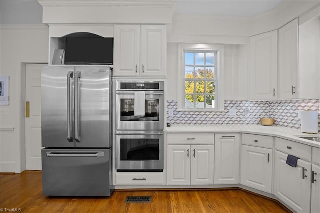 kitchen with appliances with stainless steel finishes, wood finished floors, visible vents, and backsplash