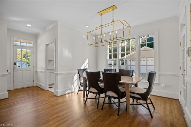 dining room featuring wood finished floors, a healthy amount of sunlight, crown molding, and a chandelier