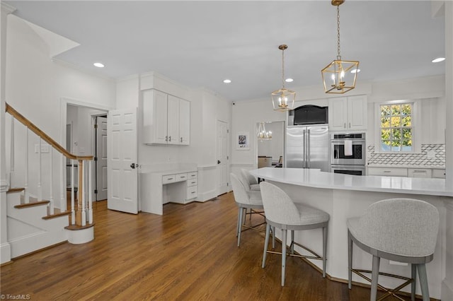 kitchen featuring a kitchen bar, white cabinets, stainless steel appliances, and light countertops