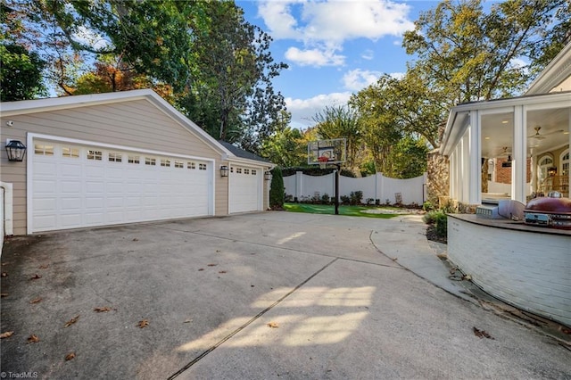 view of side of property with ceiling fan, fence, an outdoor structure, and a detached garage