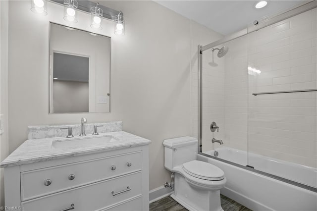 bathroom featuring toilet, enclosed tub / shower combo, vanity, and baseboards
