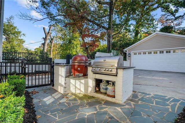view of patio / terrace with a detached garage, area for grilling, and a gate