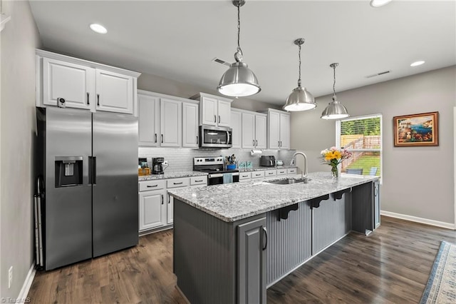 kitchen featuring appliances with stainless steel finishes, a sink, white cabinetry, baseboards, and tasteful backsplash