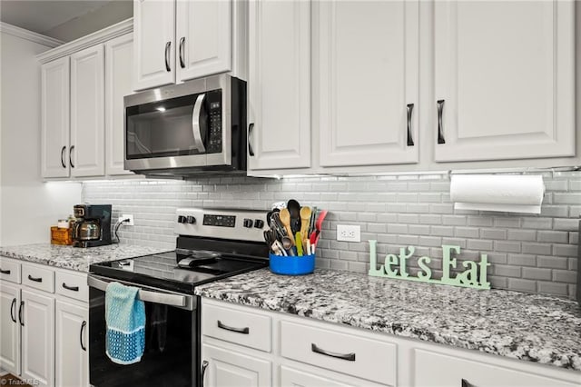 kitchen featuring stainless steel appliances, white cabinets, decorative backsplash, and light stone countertops
