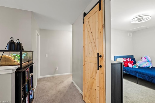 hall featuring carpet, baseboards, and a barn door