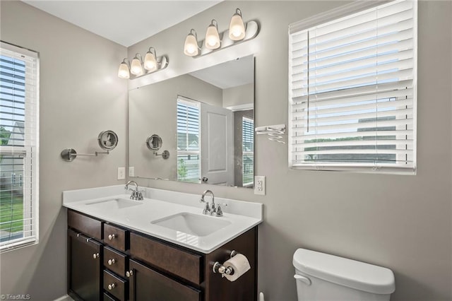 bathroom with toilet and double vanity