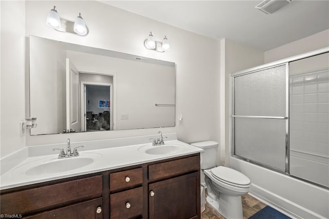 full bath with toilet, double vanity, and combined bath / shower with glass door