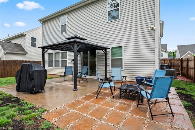 rear view of house with a gazebo, a fire pit, central AC, a fenced backyard, and a patio