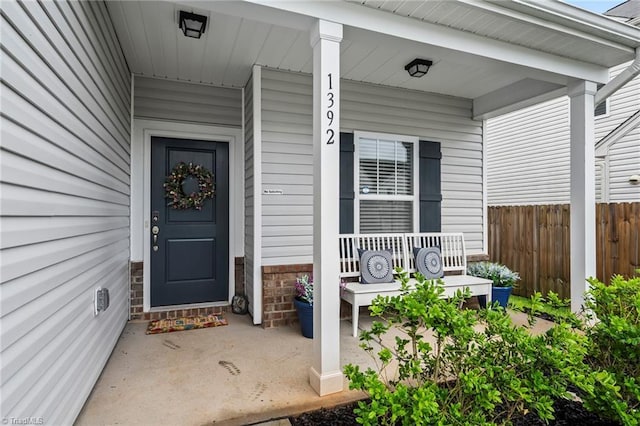 property entrance featuring a porch and fence
